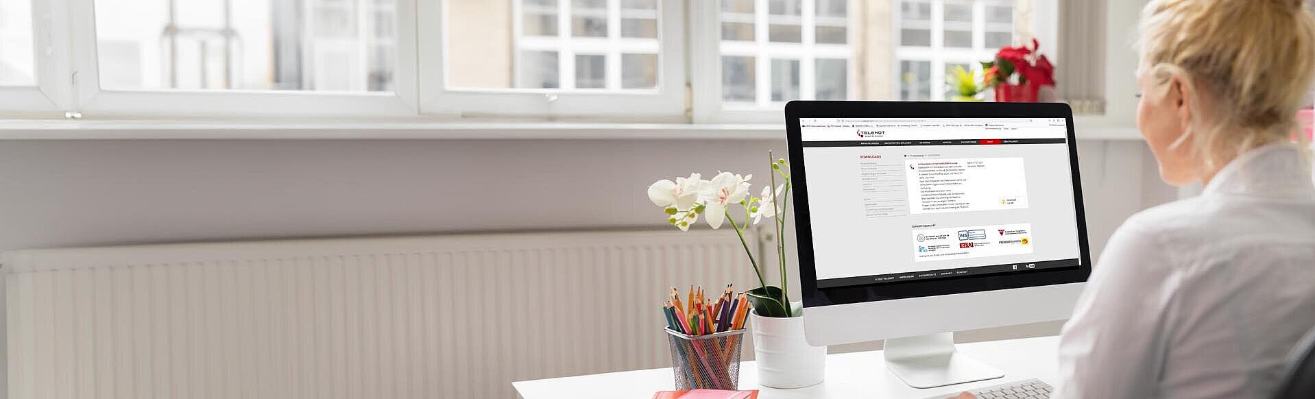 Mitarbeiterin schaut im Büro auf ihrem PC die Download-Seite an
