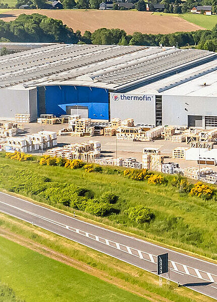 Luftaufnahme der Produktionshallen inmitten der sonnigen Landschaft.