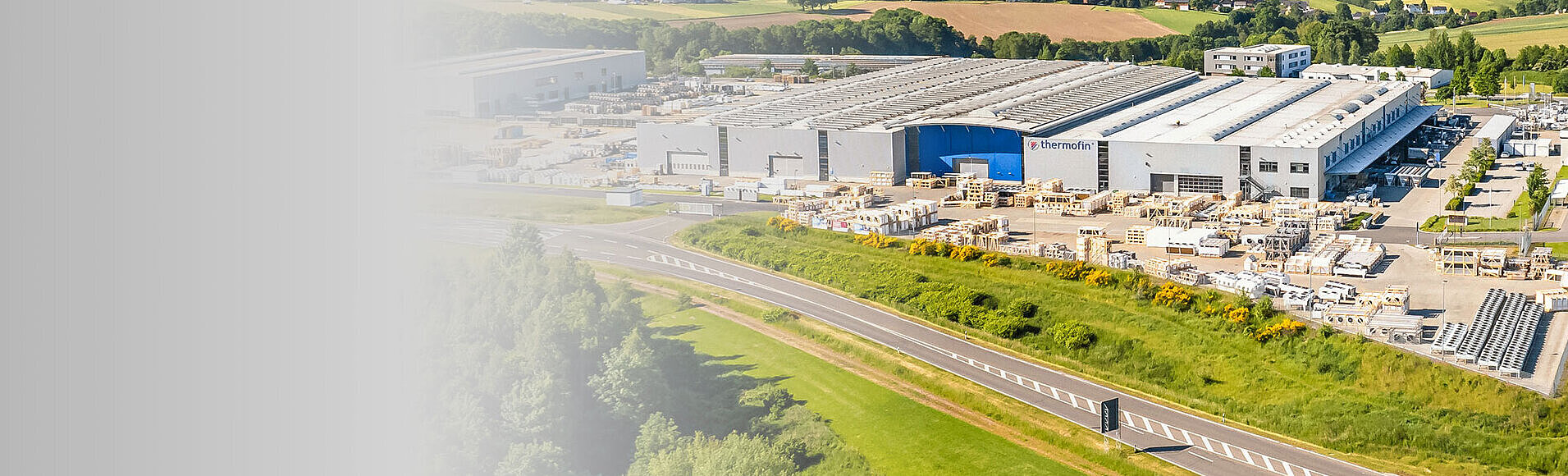 Luftaufnahme der Produktionshallen inmitten der sonnigen Landschaft.