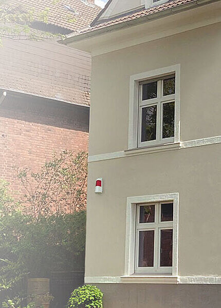 Altbau-Fassade mit optisch-akustischem Signalgeber von TELENOT, hoch an der Wand montiert.
