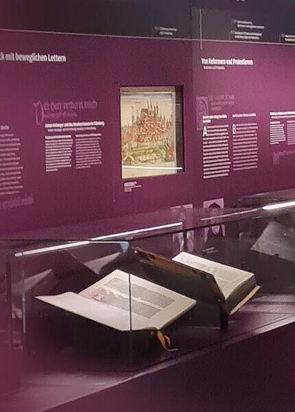 Ausstellungsraum im Museum: offene Bibel in der Glasvitrine.