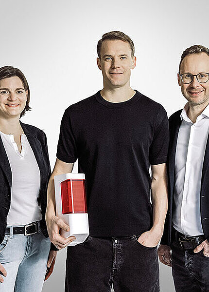 Manuel Neuer steht zwischen den Geschäftsführern Anja Wunderle und Dr. Timo Stock.