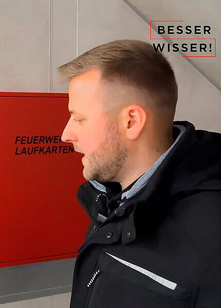 Videoausschnitt: Lisa und Nils stehen vor dem Gehäuse des Feuerwehr-Informations- und Bediensystems (FIBS)